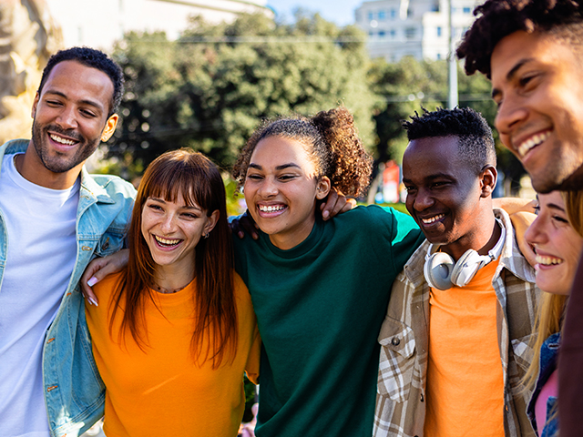 young multiracial group of college student friends standing together outside.