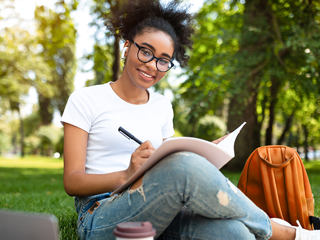 young woman writing in notebook and smiling